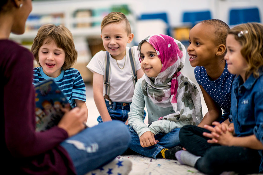 Diverse group of children in a classroom being read a story