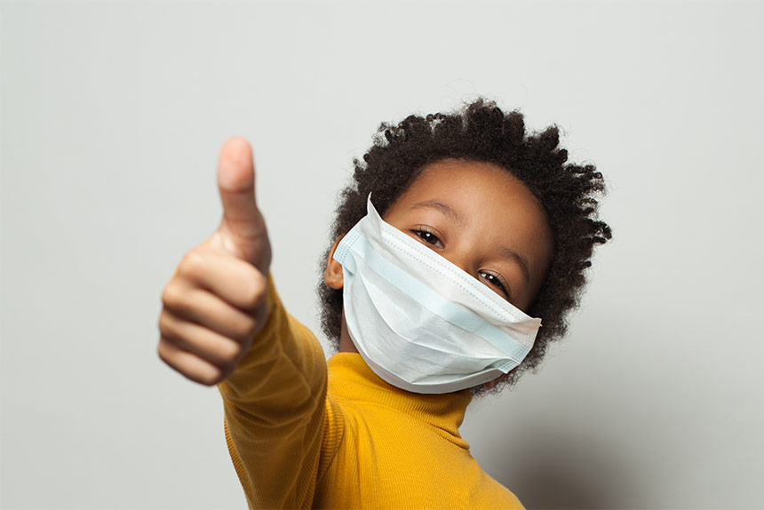 Photo of African American boy wearing a mask giving a thumbs up