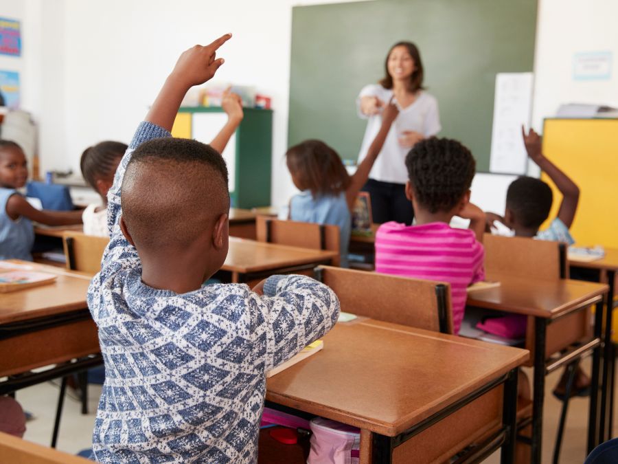 Children raising their hands in class.