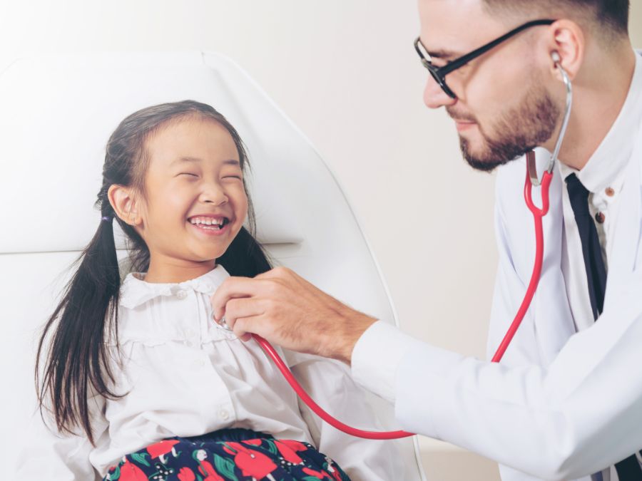 Doctor listening to youth girls heart with stethoscope.