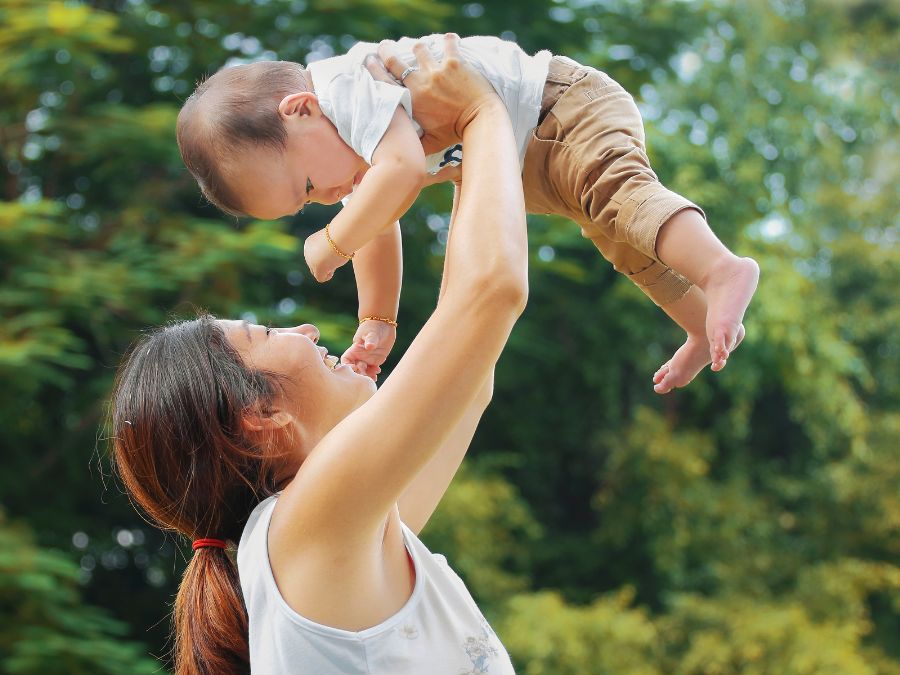 Mother lifting up small baby.