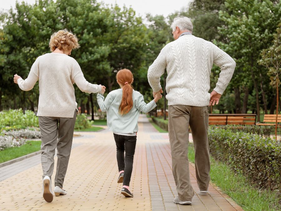 Grandparents holding hands with grandchild.