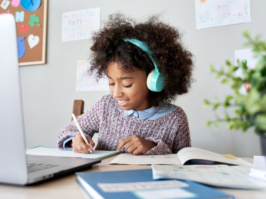 Young girl taking notes and watching a virtual course.