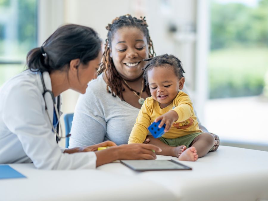 Doctor sitting with mom and baby at table.