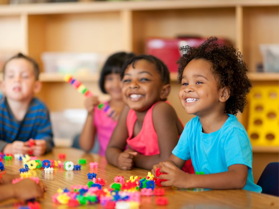 Children smiling and playing with blocks.