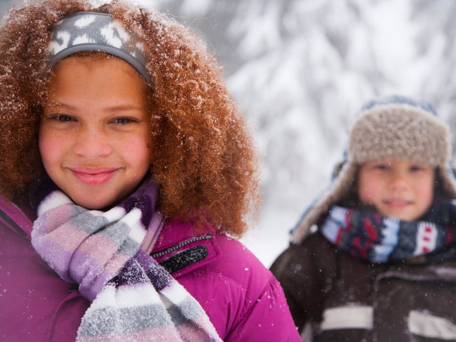 Two youths smiling while it snows.