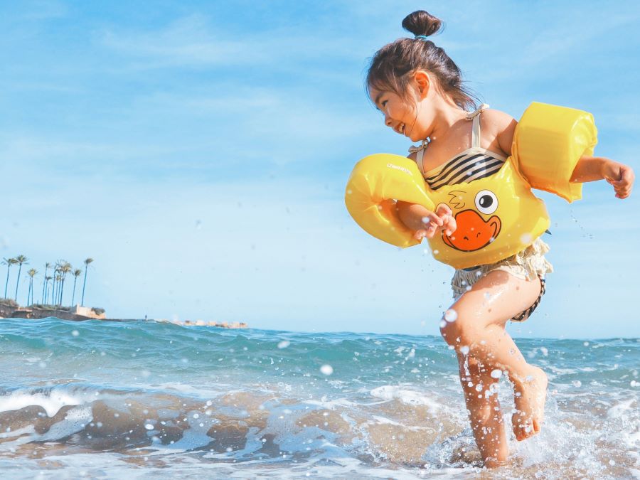 Child playing in the water on a beach.