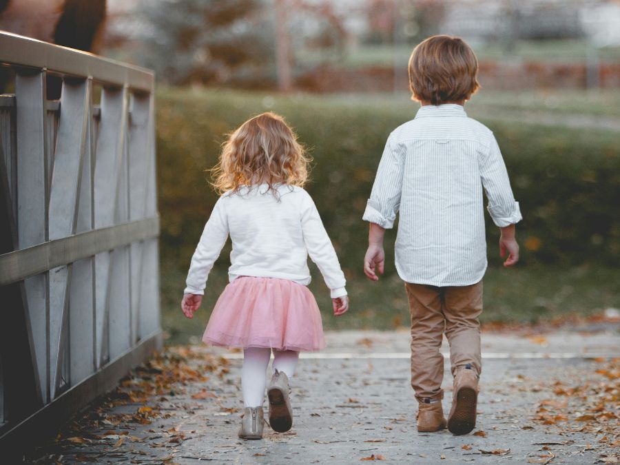 Two children walking across a bridge.